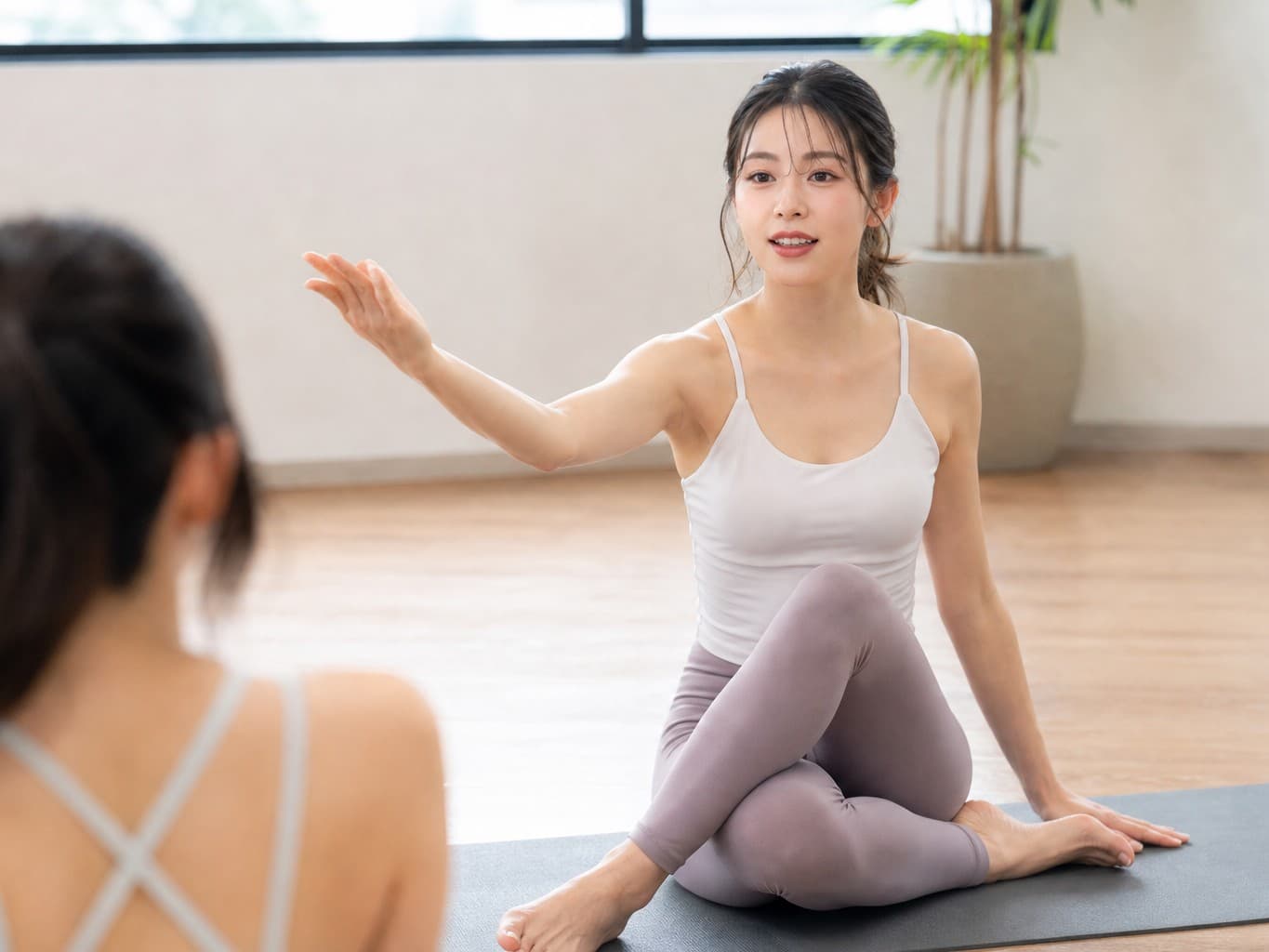 ポーズを指導するヨガインストラクター - Yoga instructor demonstrating a pose in a studio