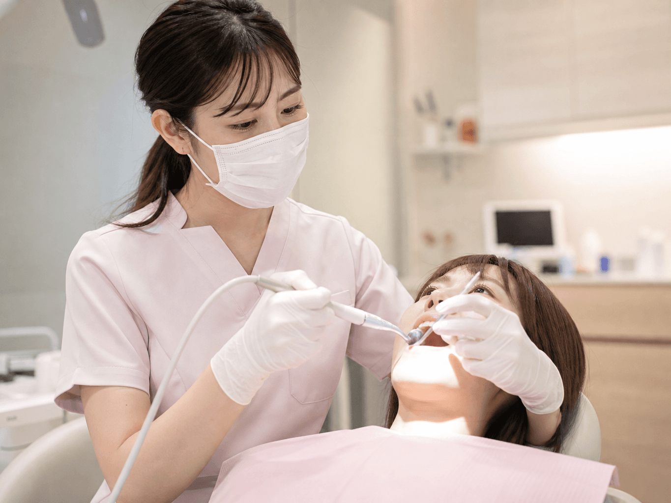歯のクリーニングをする歯科衛生士 - Dental hygienist cleaning a patient's teeth
