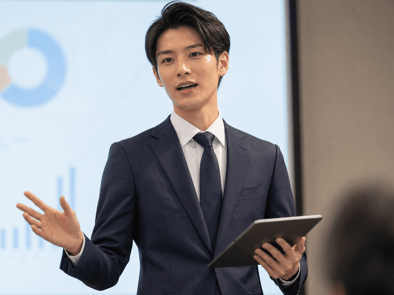 タブレットで投影資料を解説する発表者 - Presenter Explaining Projected Data with a Tablet
