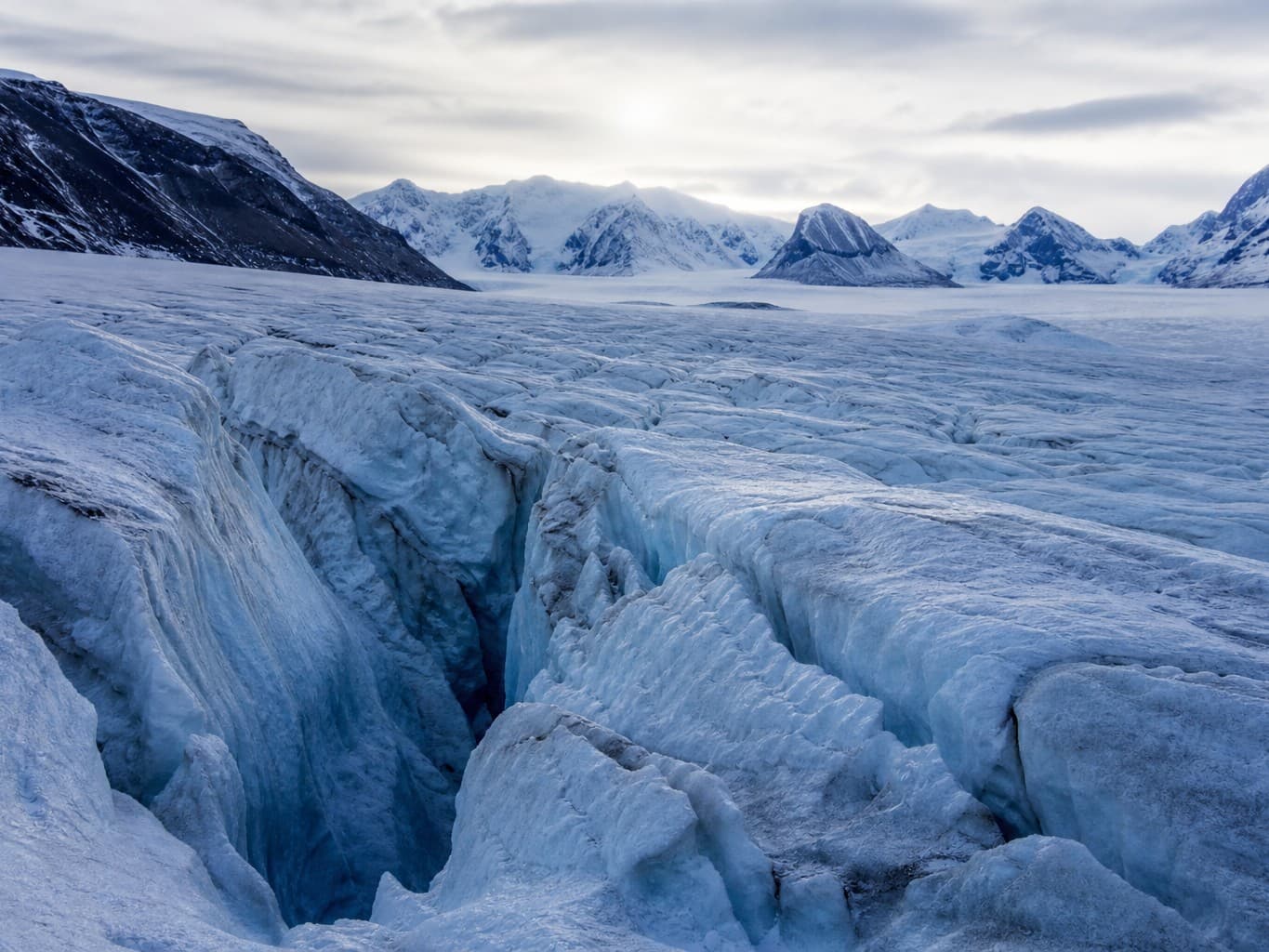 青白く輝く氷河のクレバス - Deep crevasses carved into a glowing blue glacier