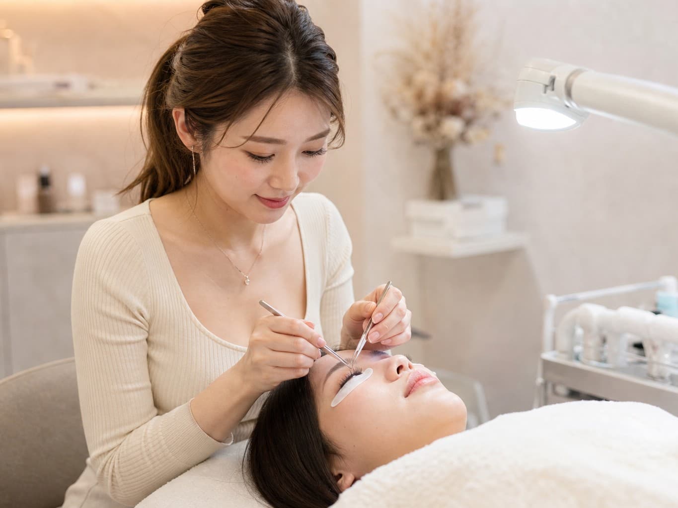 まつげエクステを施術するアイリスト - Eyelash technician applying lash extensions