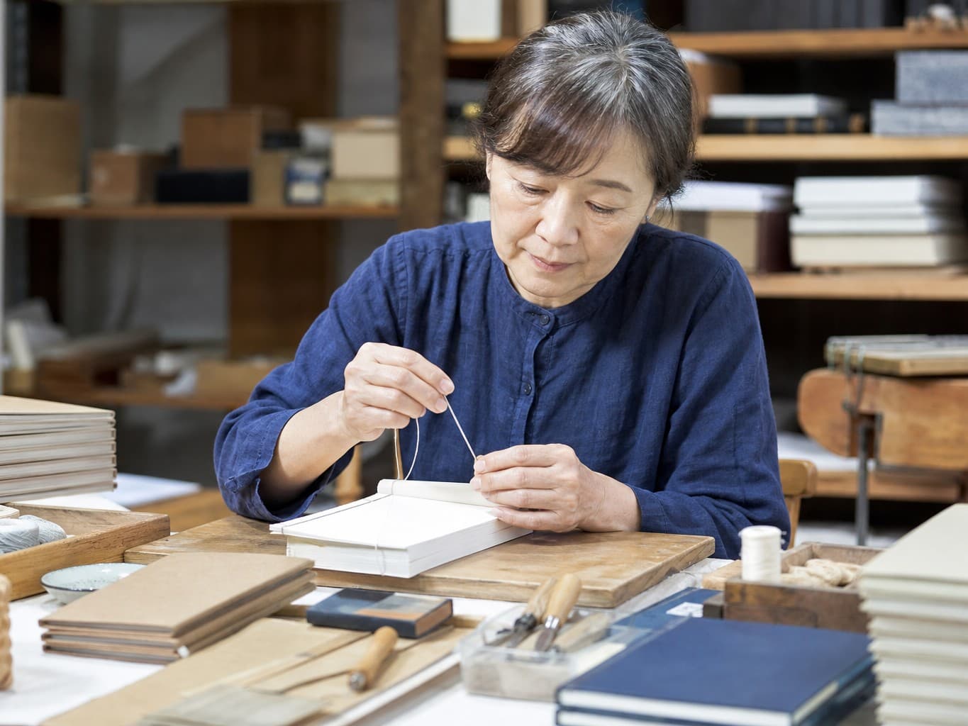 糸を綴じて本を作る製本職人 - Bookbinder hand-sewing a book