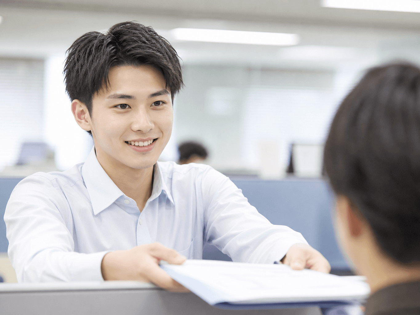 仕切り越しに書類を手渡すオフィスワーカー - Office worker handing documents over a partition