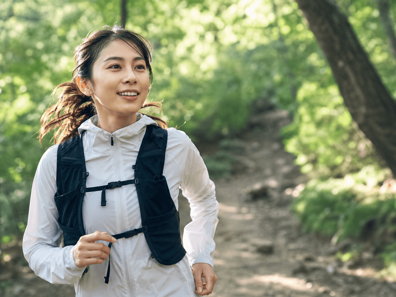 森の遊歩道を走るトレイルランナー - Trail runner jogging through a forest path in the morning