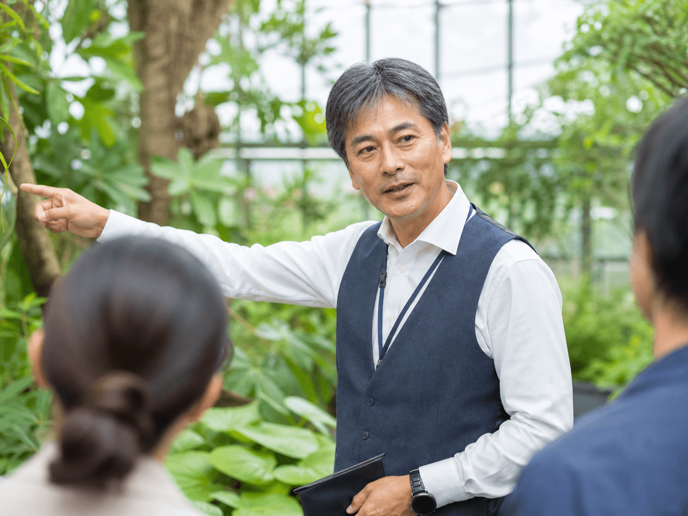 植物園で案内をするガイド - Botanical Garden Guide Explaining Plants to Visitors