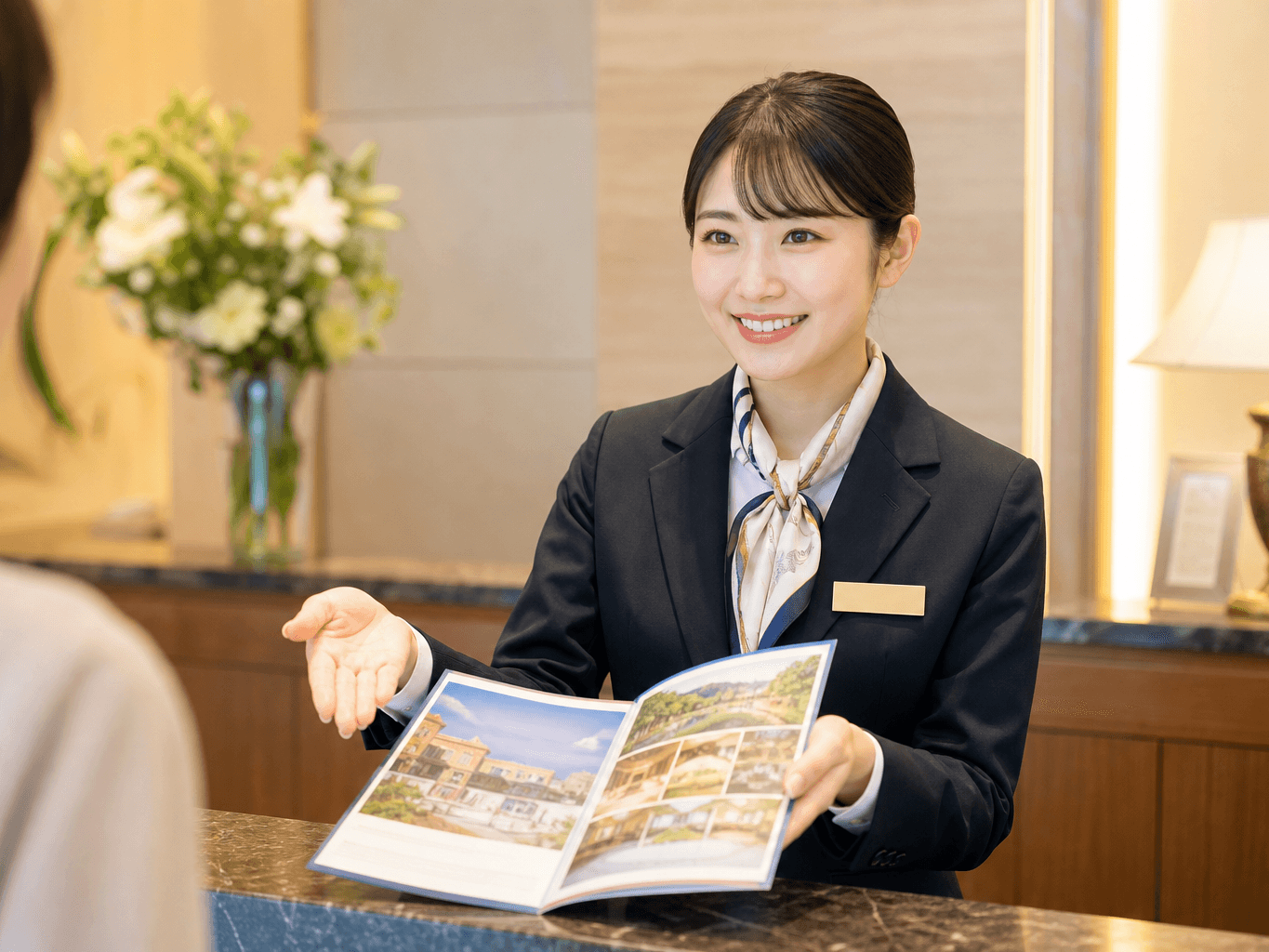 ホテルのフロントで案内する女性スタッフ - Hotel Receptionist Presenting a Brochure at the Front Desk