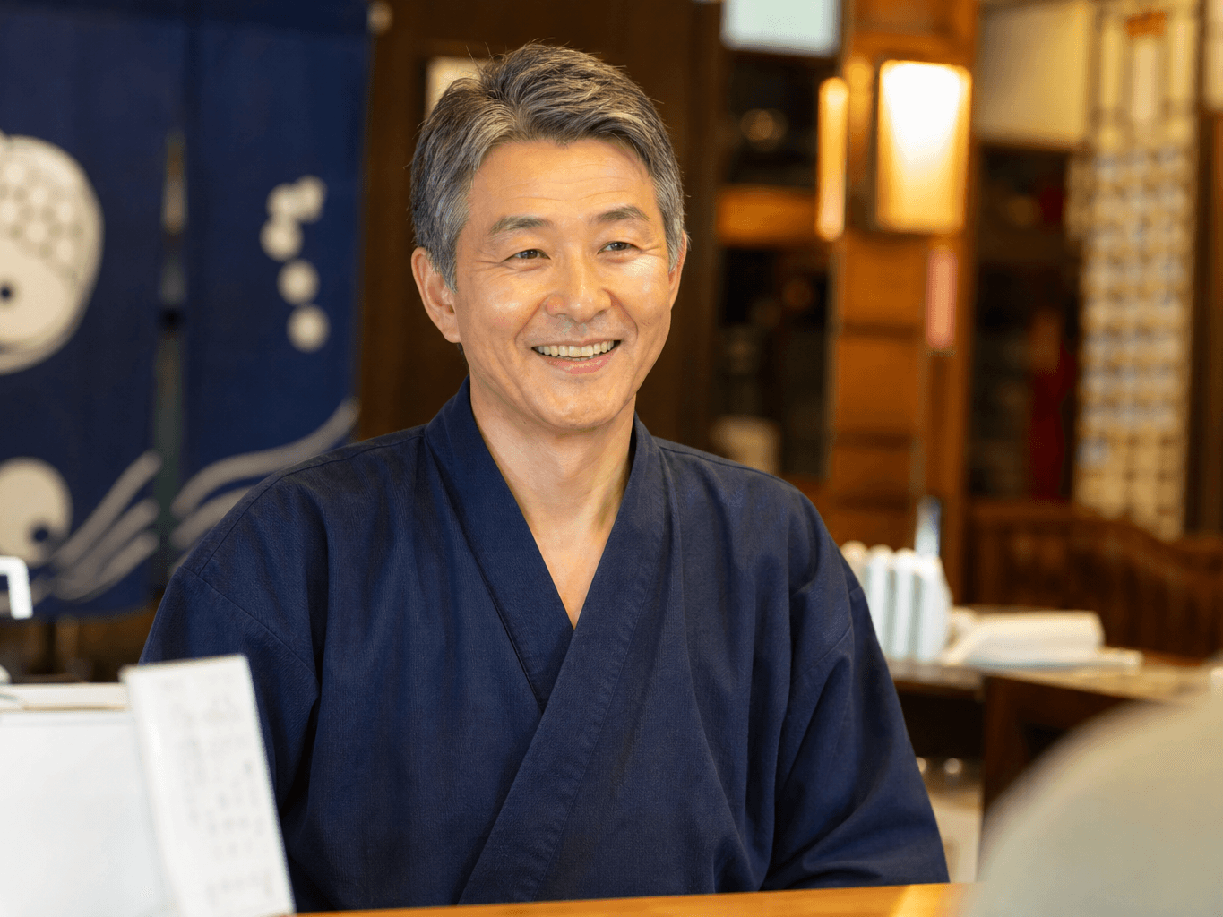 番台で受付をする銭湯の店主 - Bathhouse Attendant Greeting a Customer