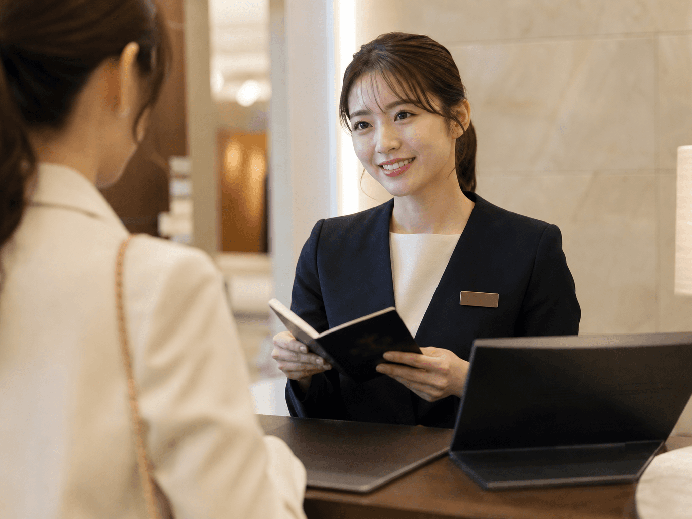 チェックイン手続きをするホテルフロントスタッフ - Hotel front desk staff assisting a guest with check-in