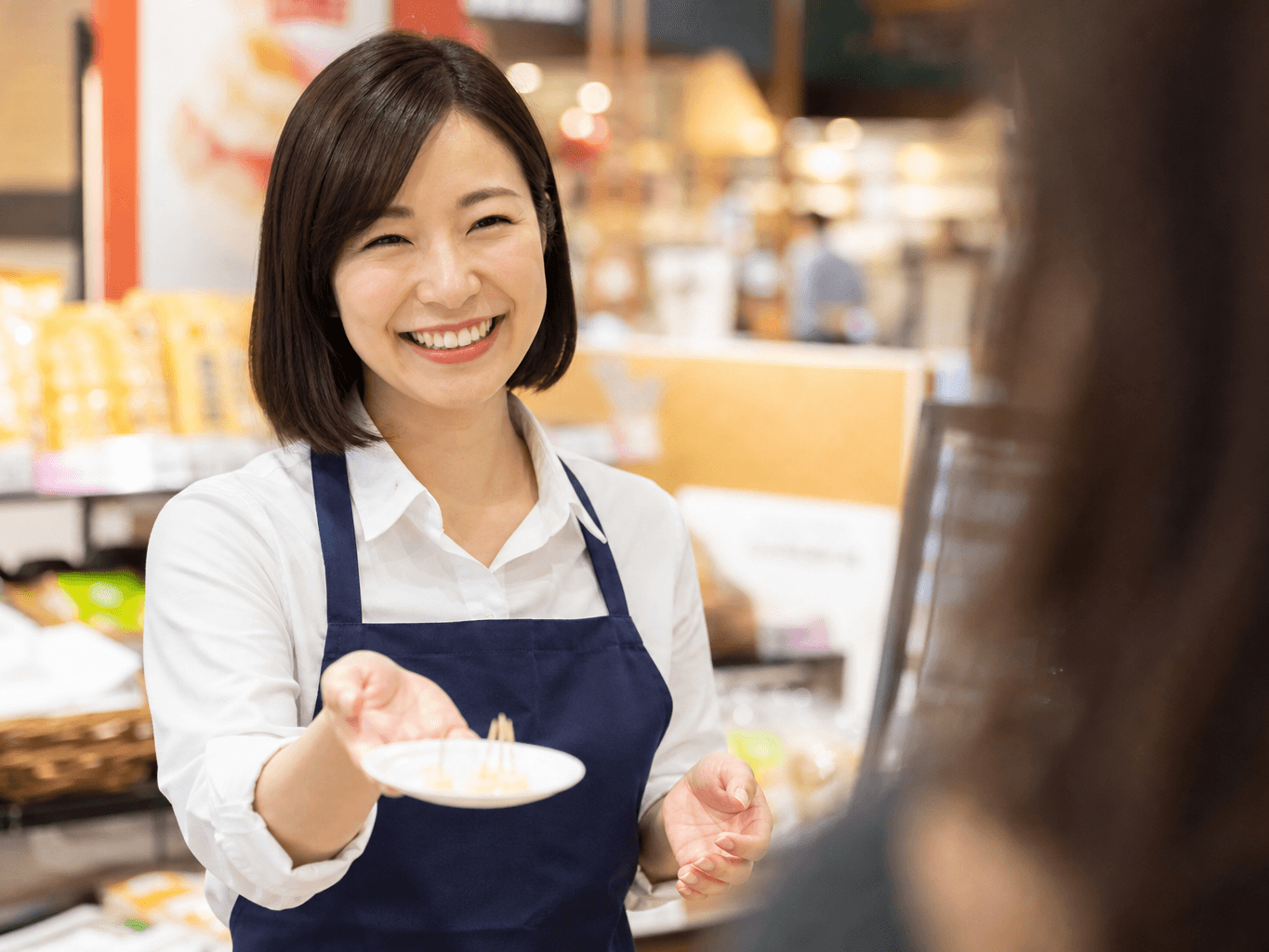 試食コーナーで案内をするスタッフ - Store Staff Offering Samples at a Supermarket