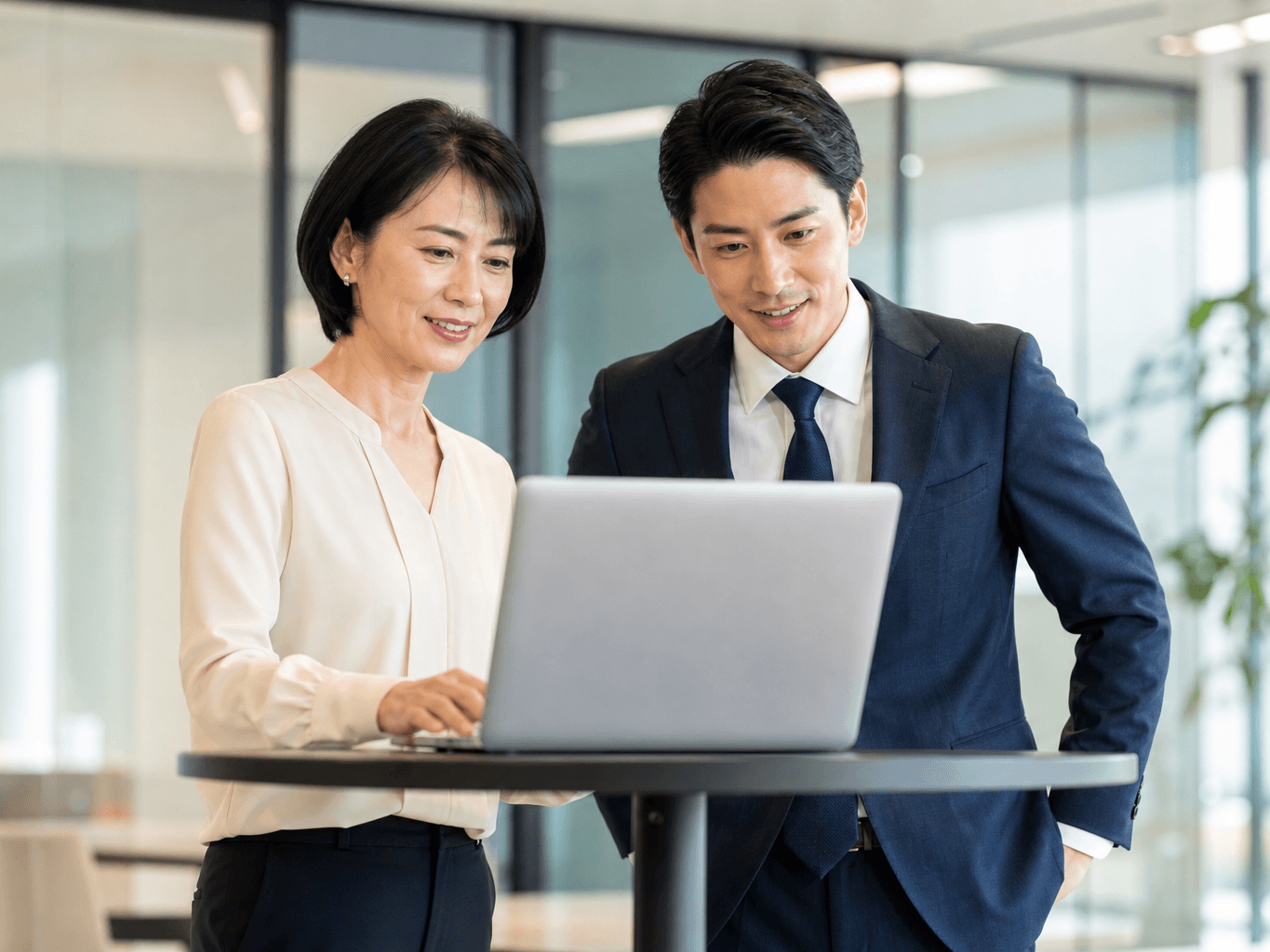 スタンディング席でPCを囲む男女社員 - Colleagues Collaborating at a Standing Table