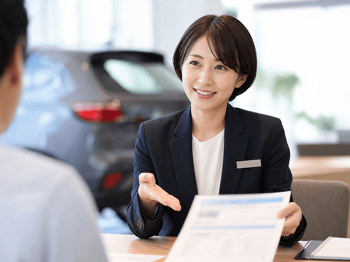 商談席で書類を丁寧に説明する女性スタッフ - Female Staff Explaining Documents at Car Dealership