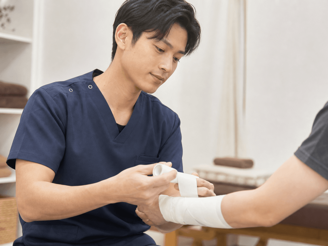 腕にテーピングを施す柔道整復師 - Judo therapist applying tape to a patient's arm