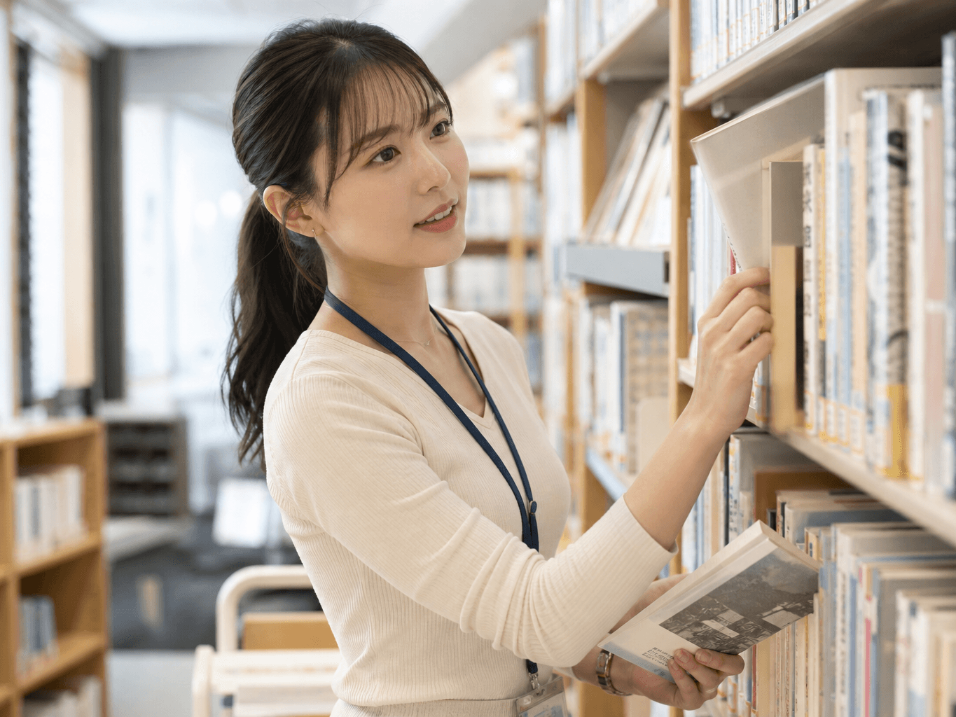 書架で本を整理する図書館司書 - Librarian organizing books on a library shelf